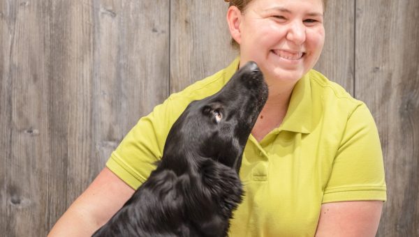Teammitglied der Kleintierpraxis Mosbach mit einem schwarzen Hund, der zu ihr aufschaut